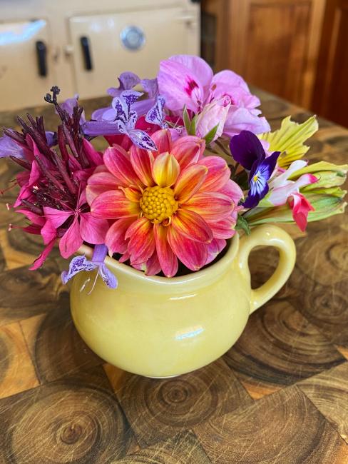 Posy of brightly coloured flowers in a yellow jug